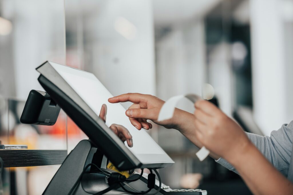 Shop assistant using a touchscreen EPOS terminal at the till