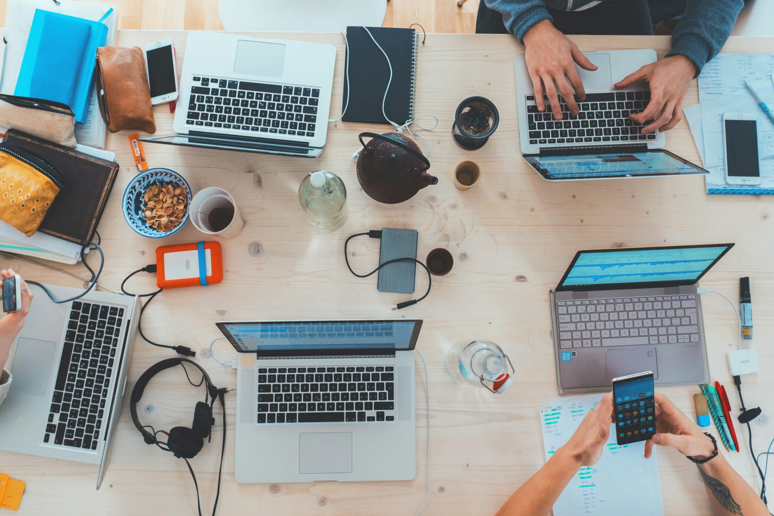 End-user devices in use: a team working at a shared table with laptops, smartphones and a headset