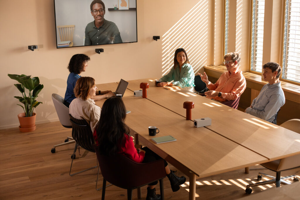 Huddly video conferencing: a team in a meeting room with a remote colleague on screen